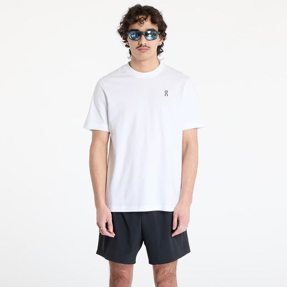 Man wearing white On Graphic-T shirt with dark shorts and sunglasses
