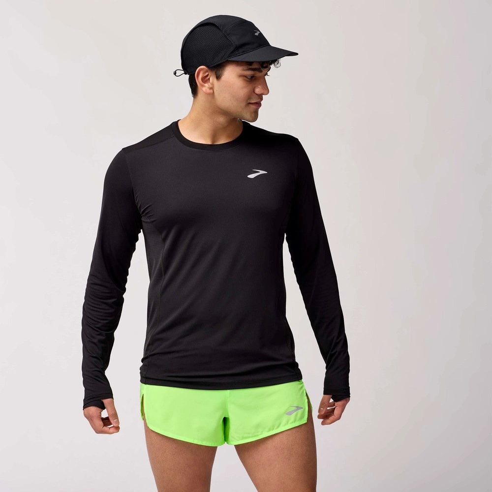 Male model wearing Brooks Atmosphere Long Sleeve black shirt with neon green running shorts