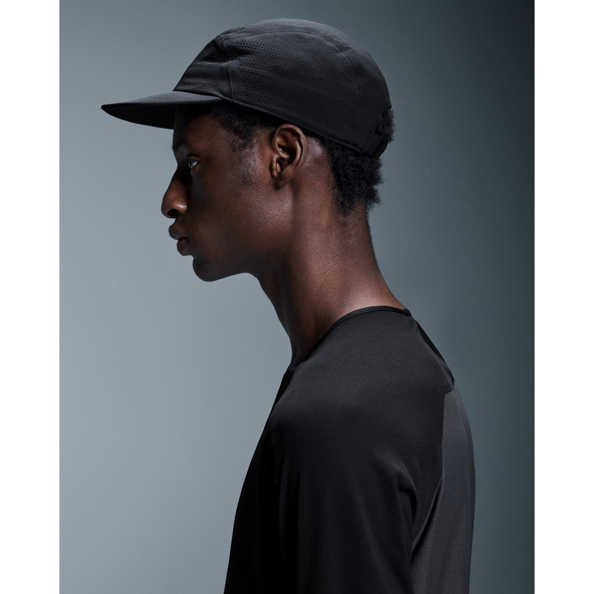 Profile view of man wearing black On Performance Cap with mesh paneling