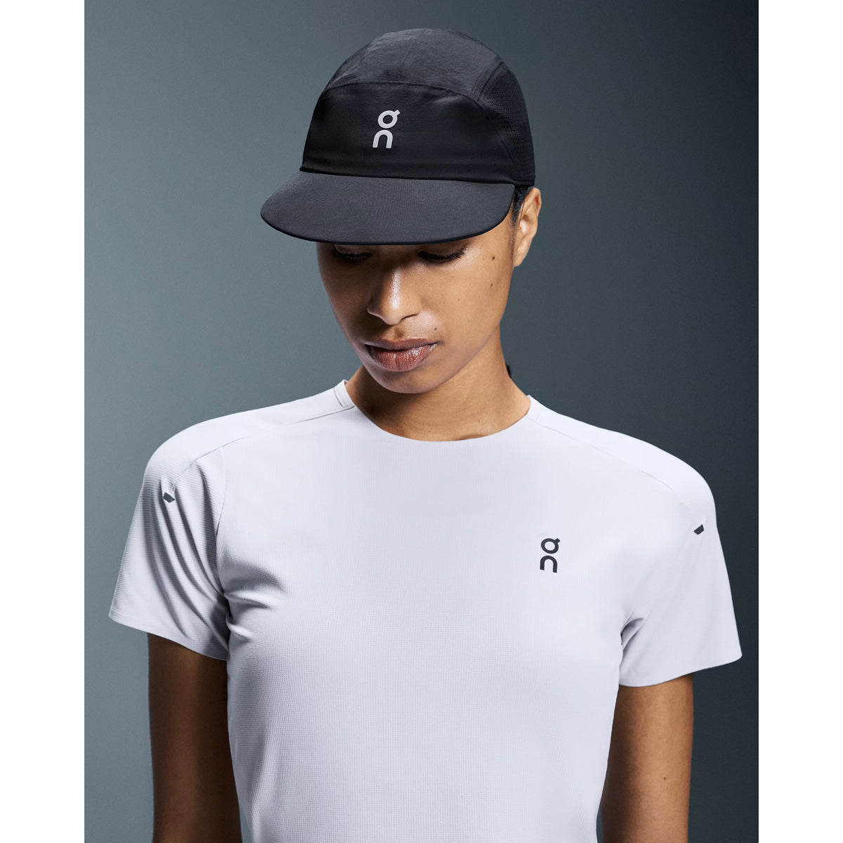Model wearing black On Performance Cap and white t-shirt against gray background