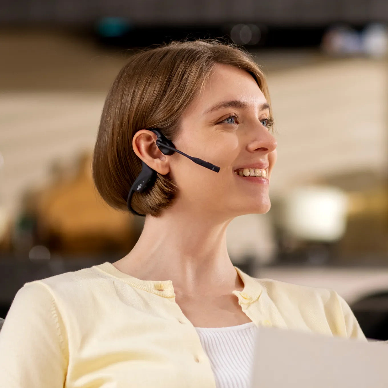 Woman wearing black Shokz OpenComm bone conduction headset with microphone boom