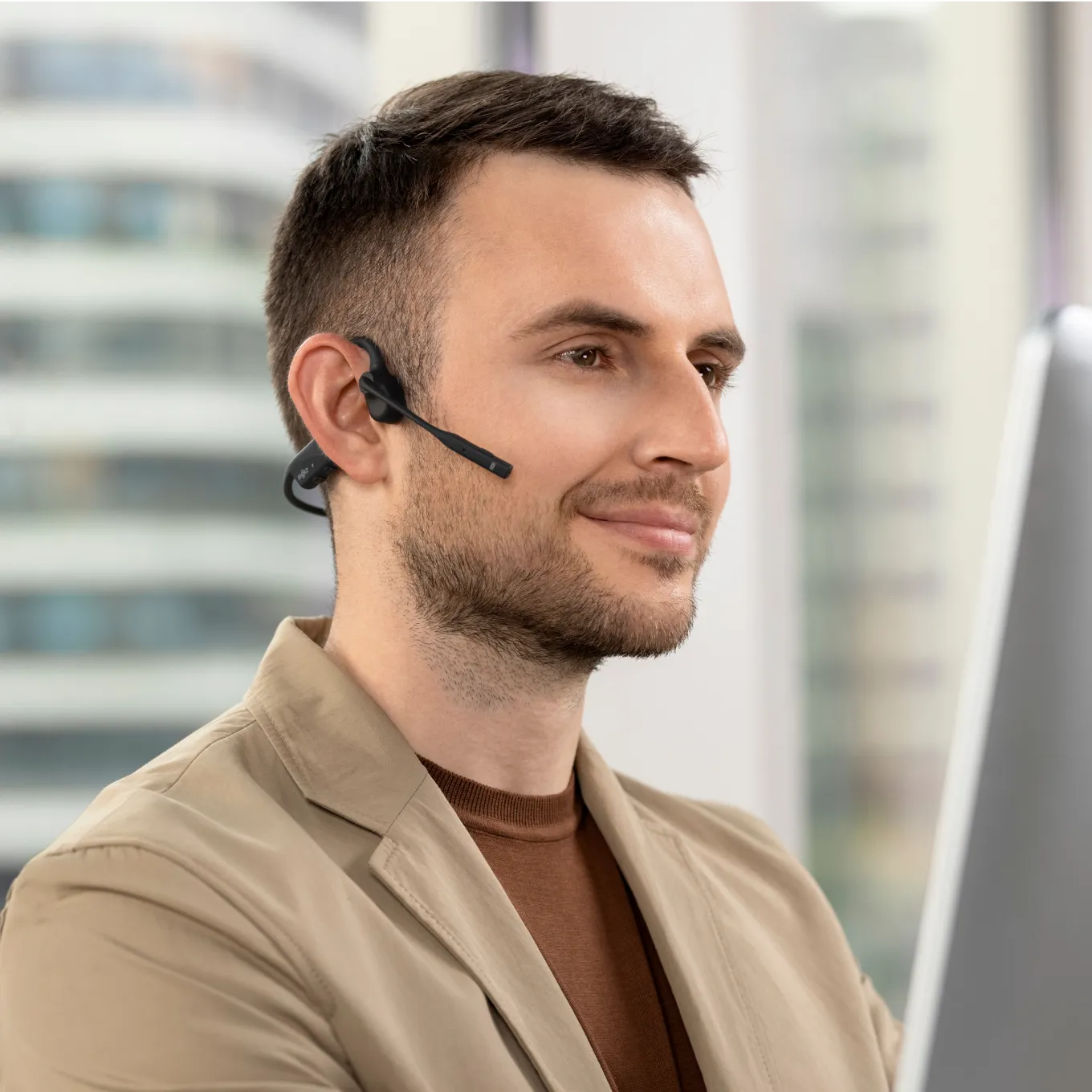 Man wearing black Shokz OpenComm bone conduction headset with microphone boom