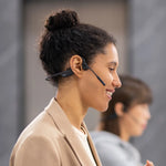 Woman wearing black Shokz OpenComm bone conduction headset with microphone boom