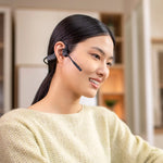 Woman wearing black Shokz OpenComm 2UC bone conduction headset with boom microphone