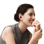 Woman wearing red Shokz OpenDots ONE earbuds, smiling in professional studio portrait