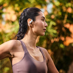 Woman wearing white Shokz OpenFit wireless earbuds during outdoor workout