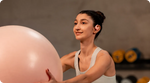 Woman wearing pink Shokz OpenFit Air earbuds during workout with exercise ball
