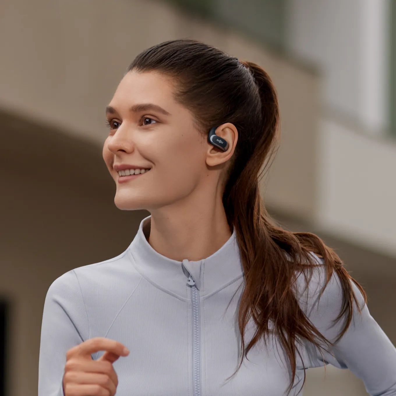 Woman wearing black Shokz OpenFit Air wireless earbuds during workout