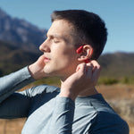 Man wearing red AfterShokz OpenRun bone conduction headphones outdoors in natural lighting