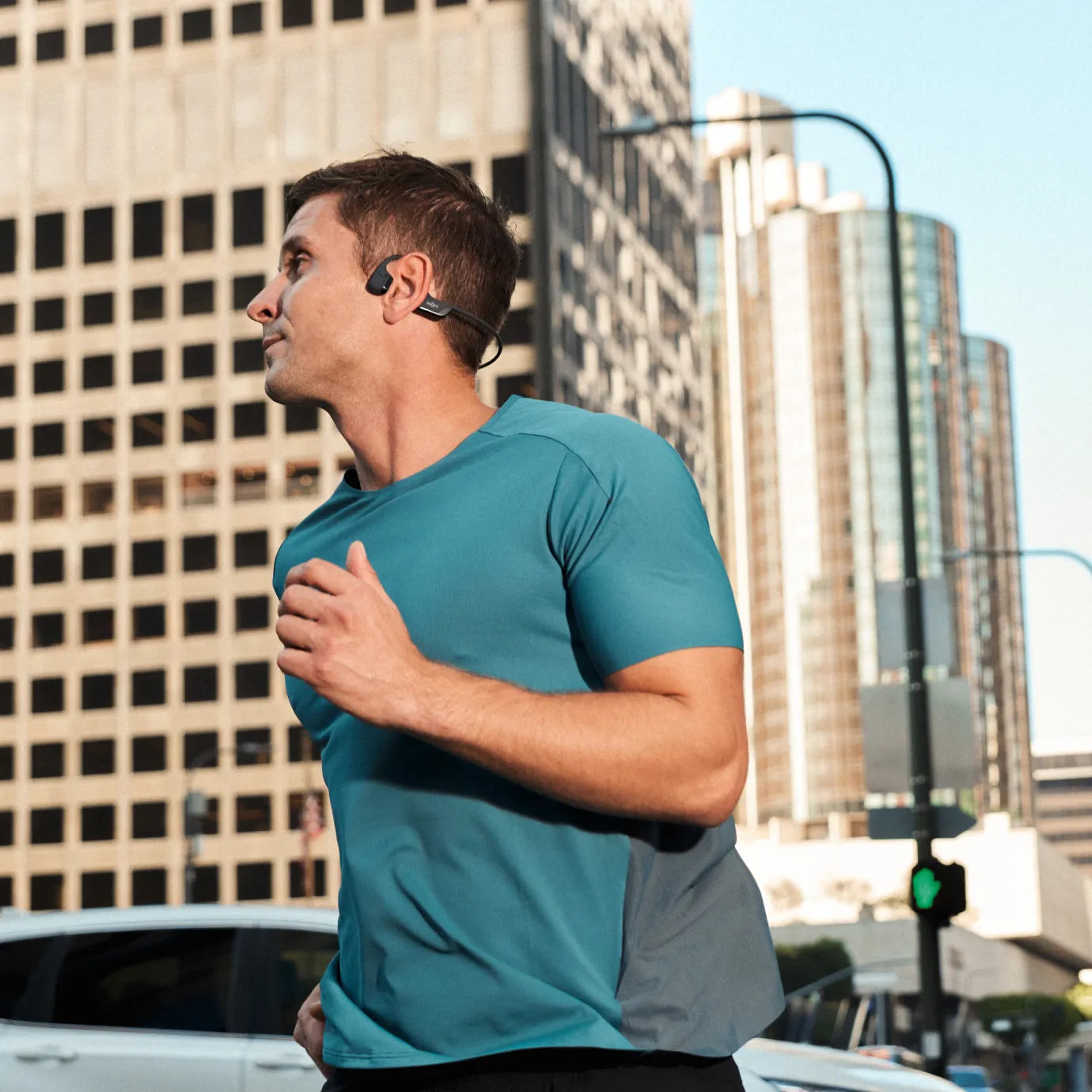 Man running in city wearing black Shokz OpenRun Pro 2 bone conduction headphones