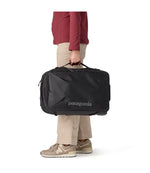 Person carrying Patagonia Black Hole MLC Wheelie 34L black bag by top handle, side view