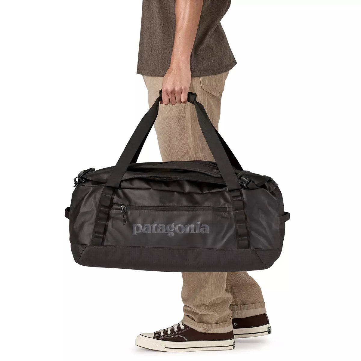 Person carrying Patagonia Black Hole Duffel 55L in black by its top handles, lifestyle shot