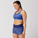 Woman wearing Brooks Dare Scoopback sports bra in periwinkle blue with matching printed shorts
