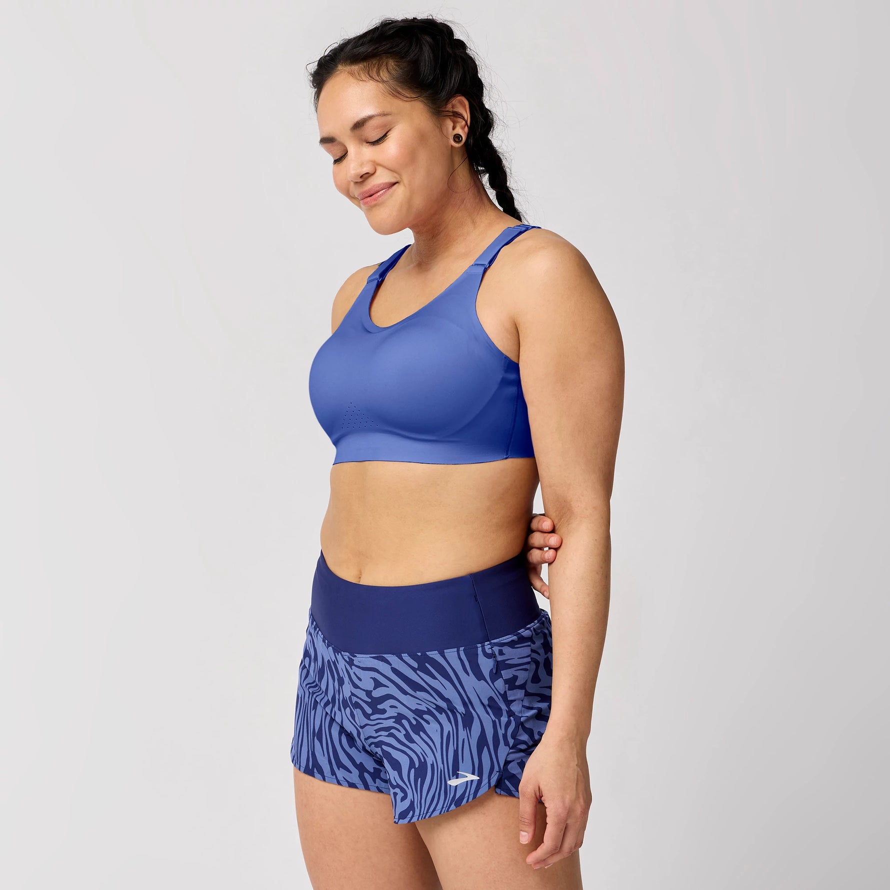 Woman wearing Brooks Dare Scoopback sports bra in periwinkle blue with matching printed shorts