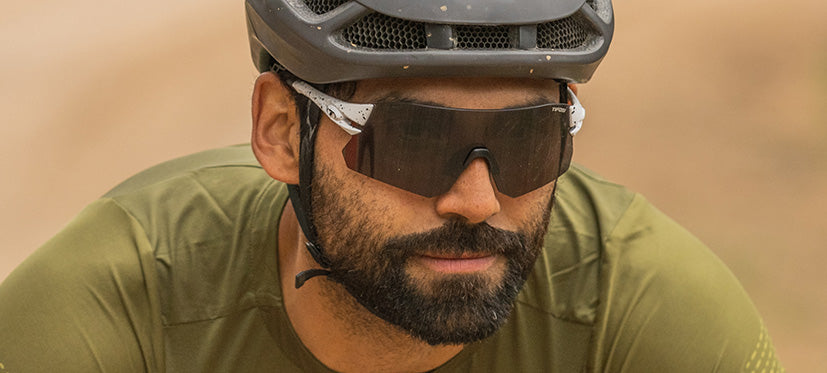 Man wearing Tifosi Rail BlackOut sunglasses with cycling helmet outdoors