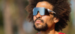 Man wearing white framed Tifosi sunglasses with blue mirrored lenses outdoors