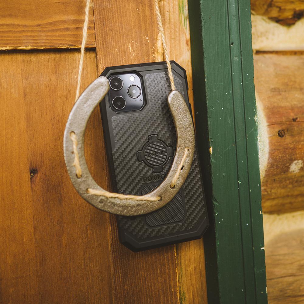 Rokform black carbon fiber iPhone case with rope lanyard hanging on wooden fence