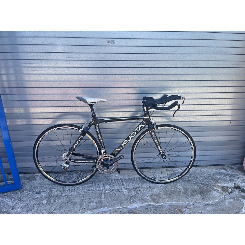 Kuota Factor carbon triathlon TT bike in black, full drive-side view with aero cockpit