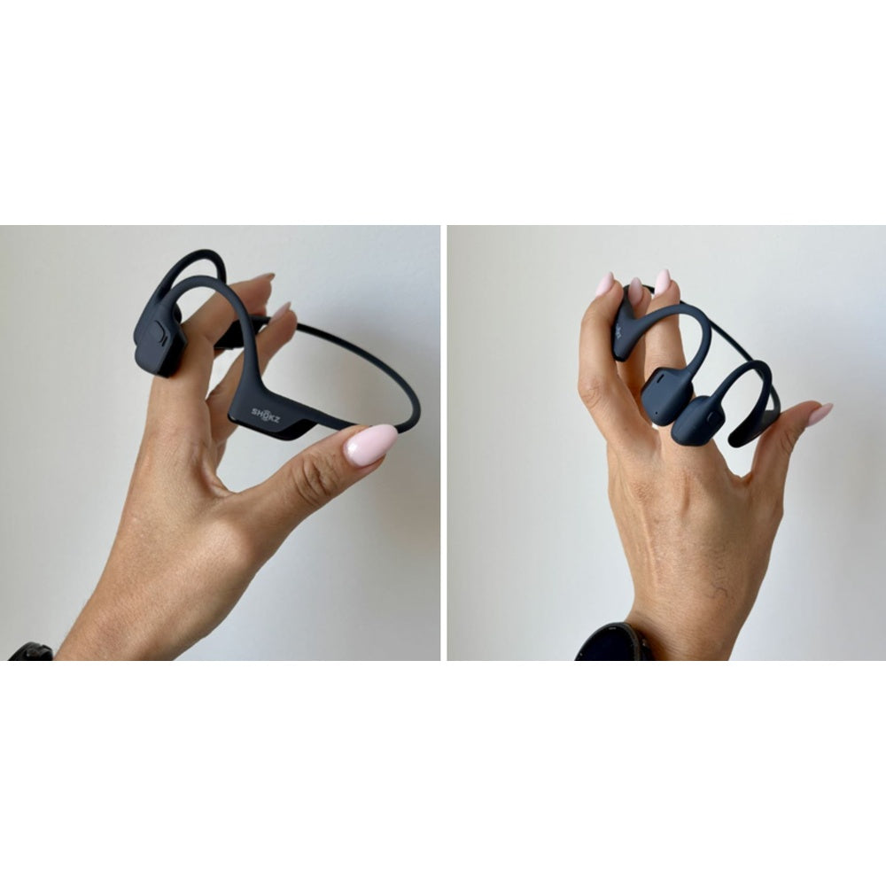 Black Shokz bone conduction headphones held in hands showing lightweight design