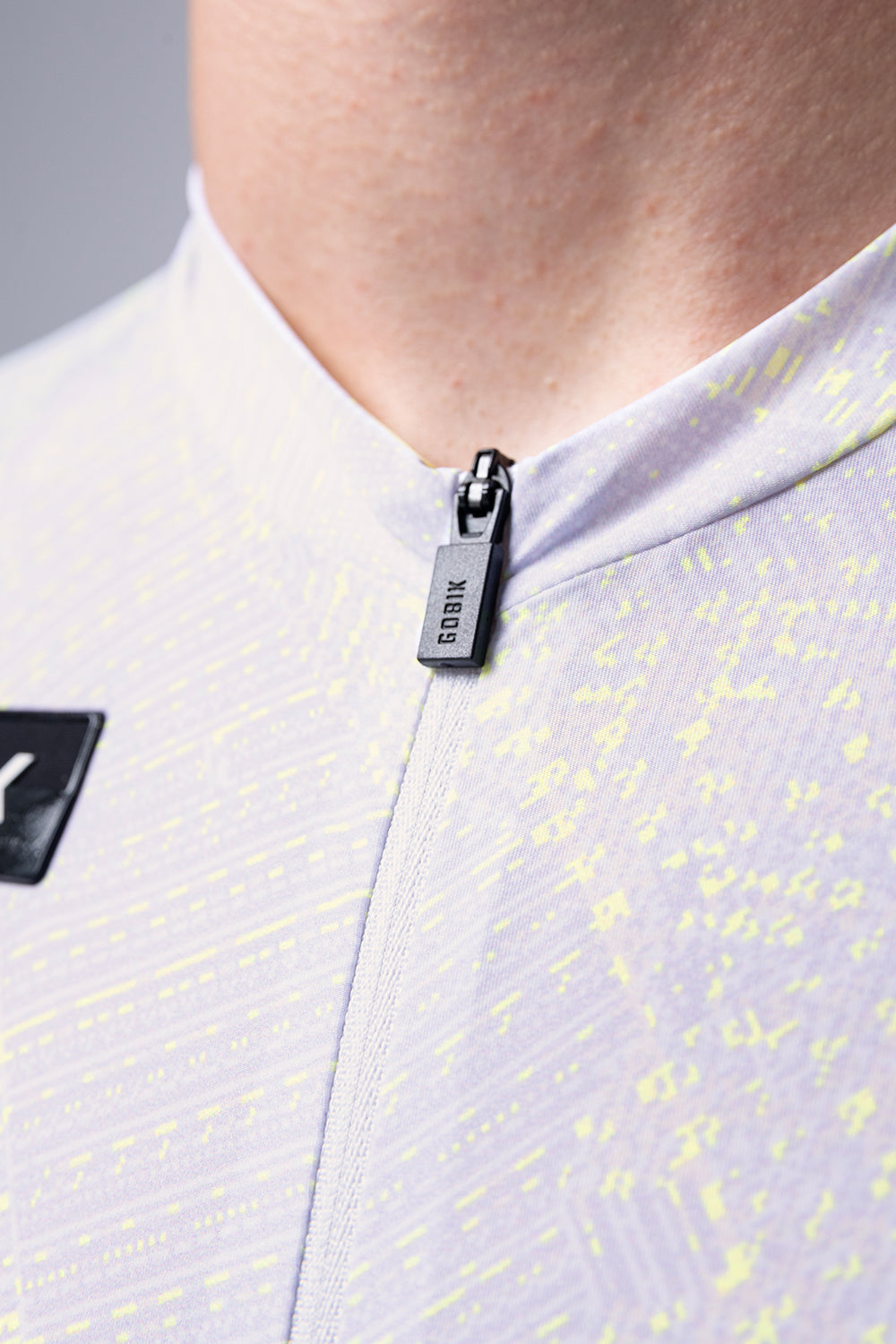 Close-up of Gobik cycling jersey zipper detail in light silver with yellow speckles