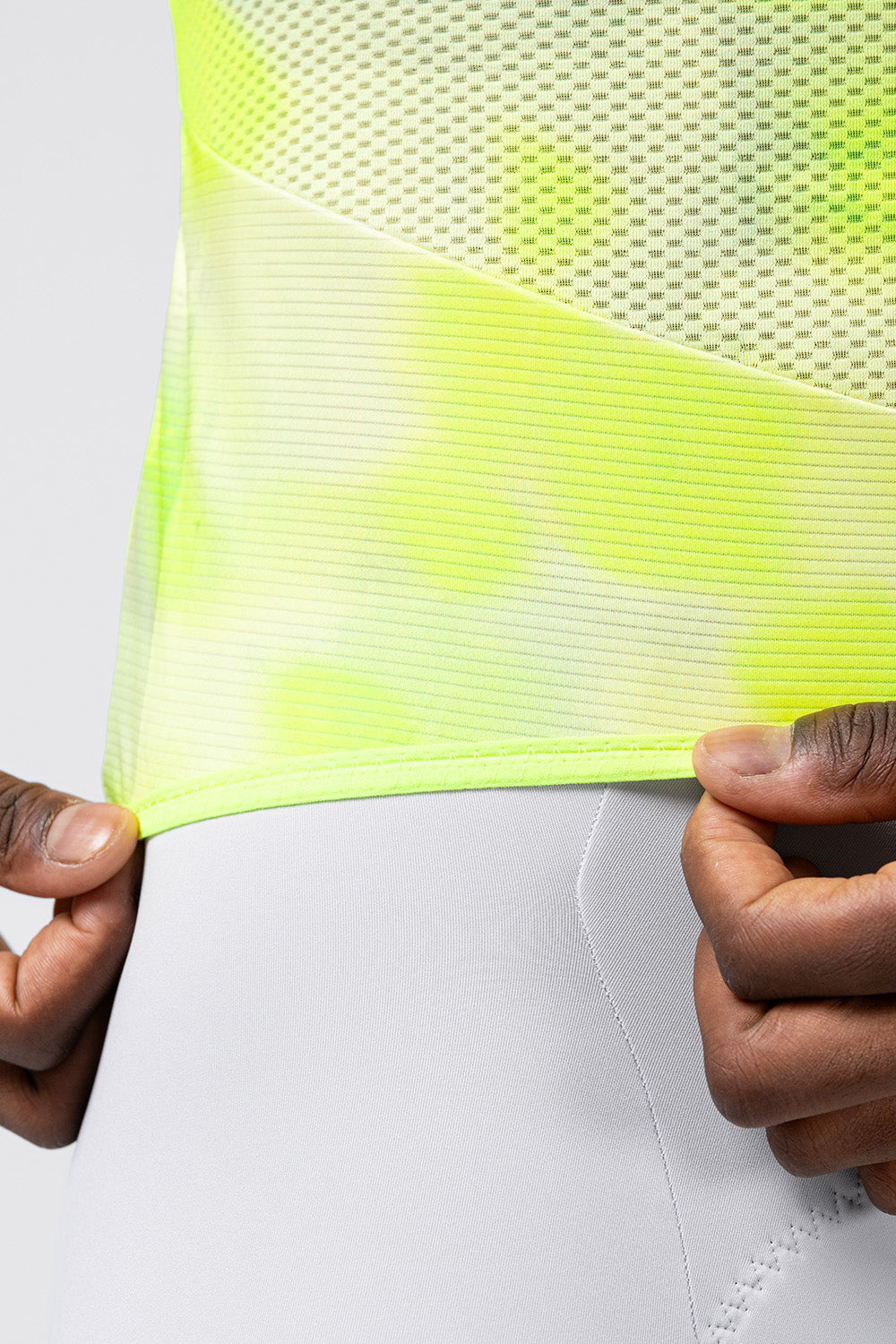 Close-up detail of Gobik Carrera 3.0 neon yellow jersey hem and mesh fabric texture