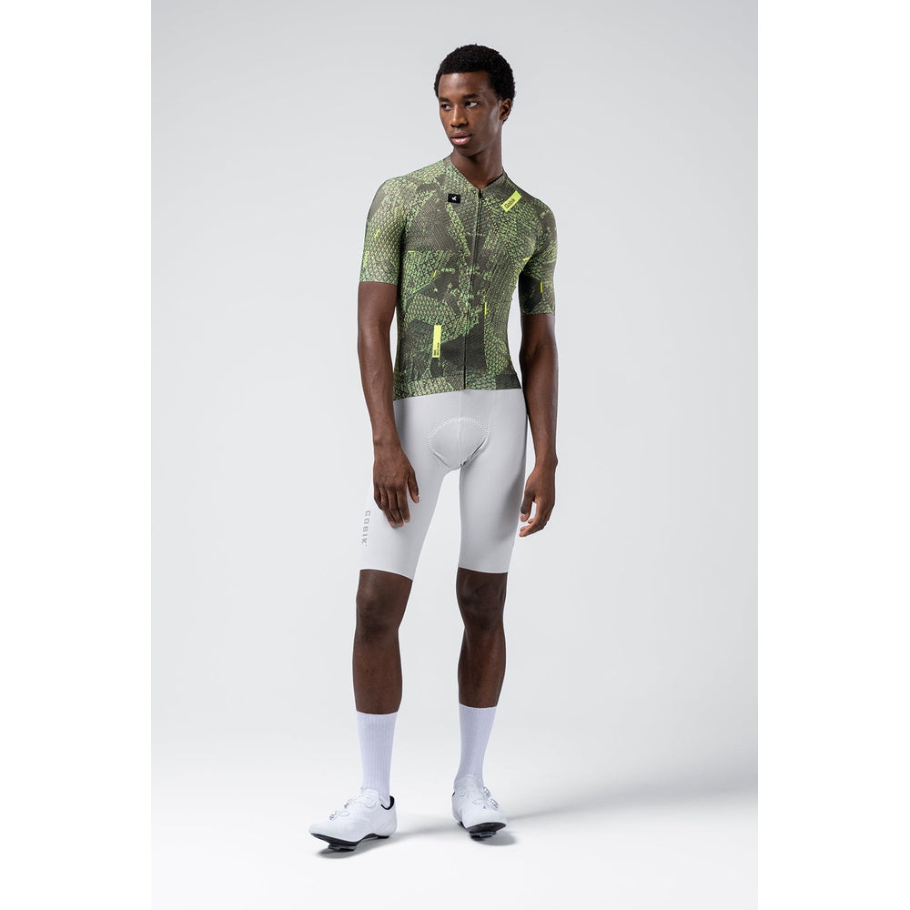 Male cyclist wearing Gobik CX Pro jersey in green grid camouflage pattern with white shorts