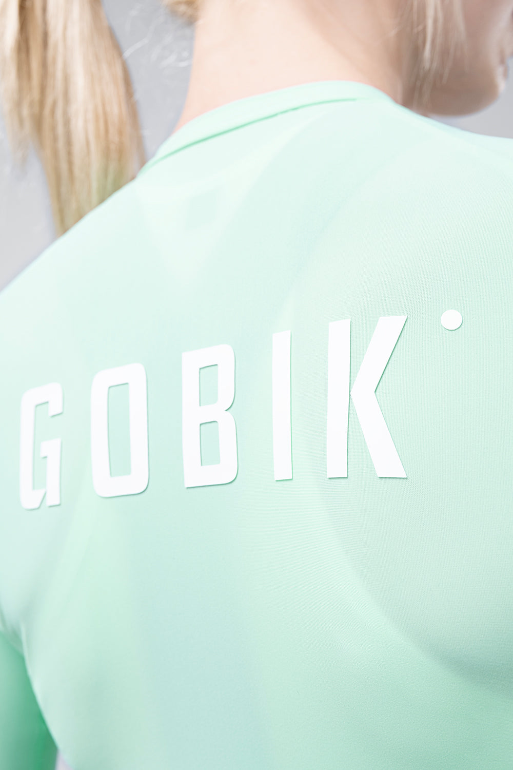 Person wearing mint green Gobik cycling jersey with white lettering