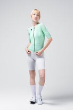 Woman wearing Gobik CX Solid short sleeve cycling jersey in mint green with gray shorts