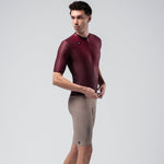 Man wearing burgundy Gobik Magnitude short sleeve cycling jersey with gray shorts