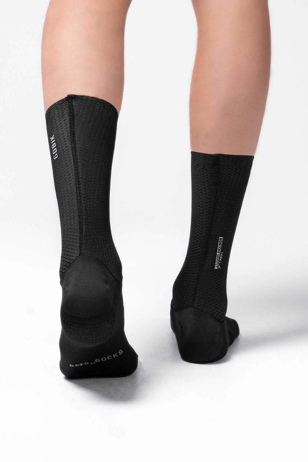 Black Gobik Vortex 2.0 cycling socks worn on legs against white background