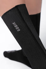 Black Gobik cycling socks worn on legs showing brand logo and textured fabric