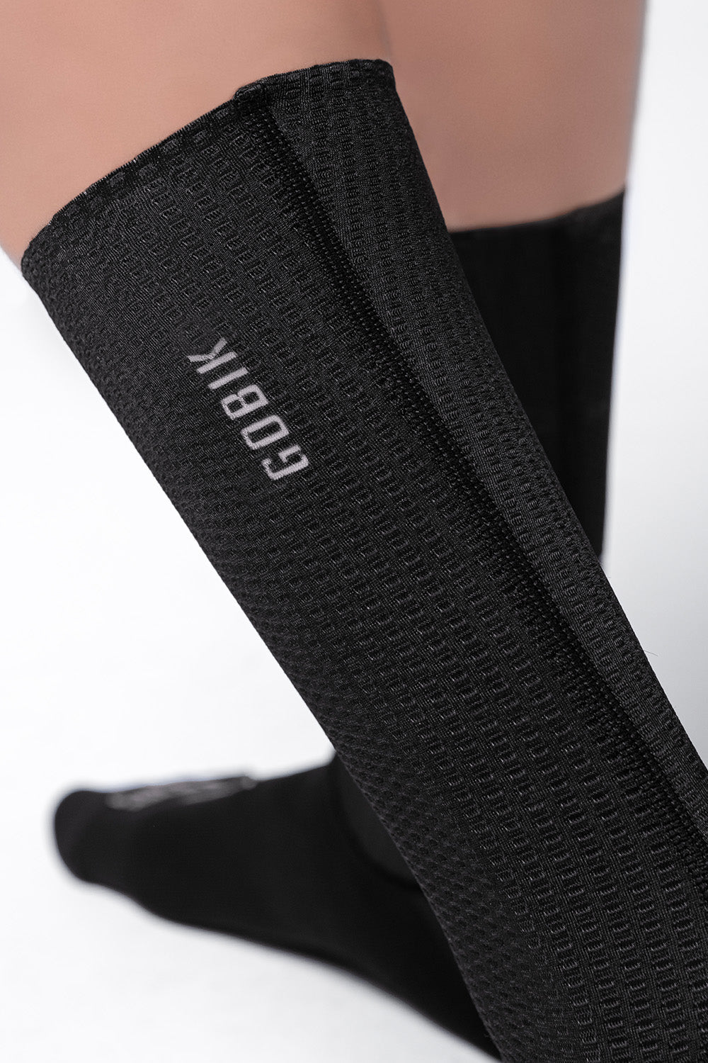 Black Gobik cycling socks worn on legs showing brand logo and textured fabric
