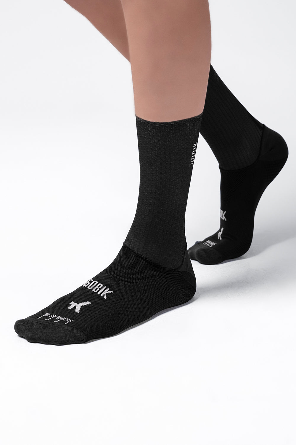 Black Gobik Vortex 2.0 cycling socks worn on feet against white background