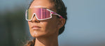 Woman wearing white Tifosi Stash sunglasses with pink iridescent lenses outdoors