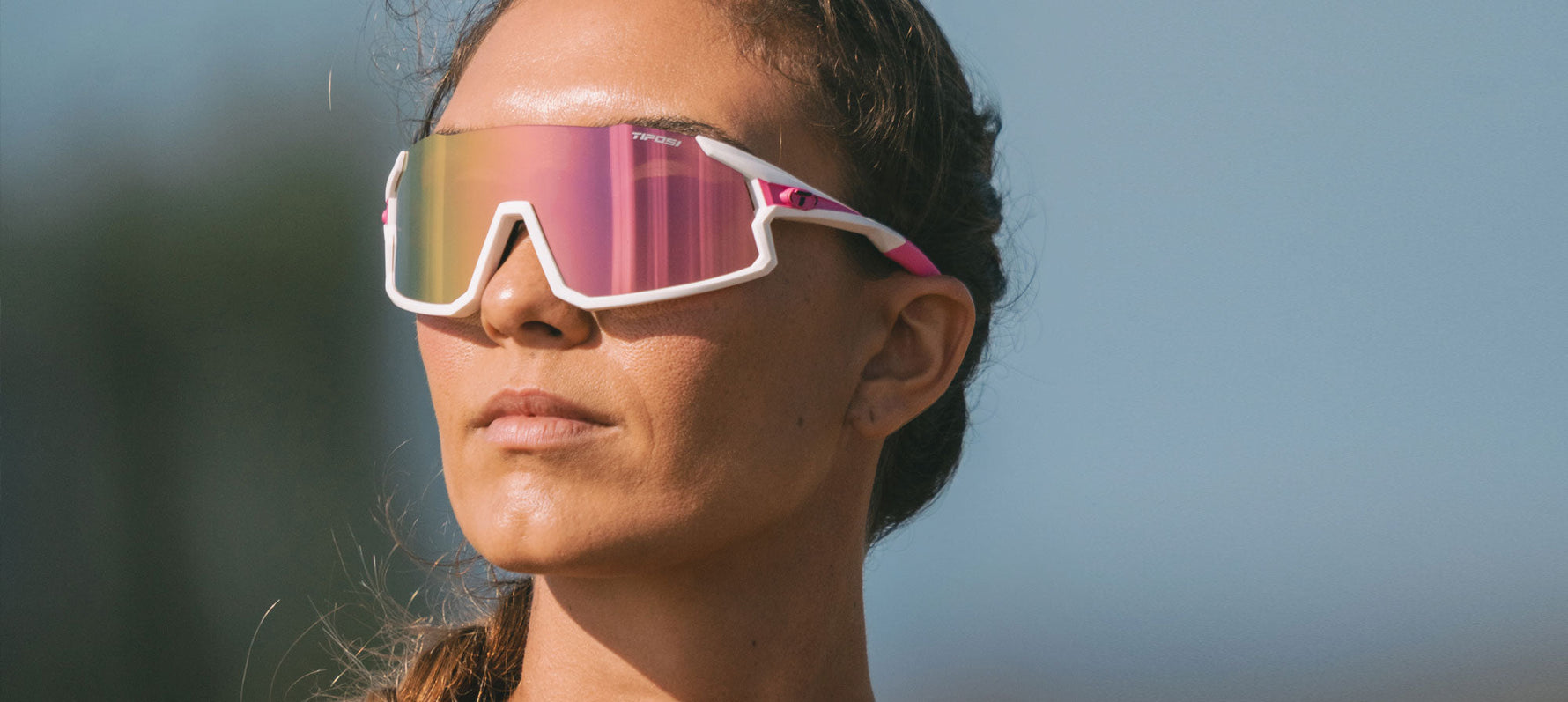 Woman wearing white Tifosi Stash sunglasses with pink iridescent lenses outdoors