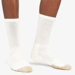Thorlos white crew socks with tan toe cushioning worn on dark-skinned legs