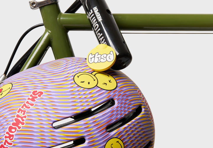 Thousand Next Youth Helmet in Lavender Sunset with swirl pattern and smiley stickers on bike