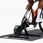Cyclist using Wahoo KICKR CORE 2 smart trainer with black flywheel on exercise mat