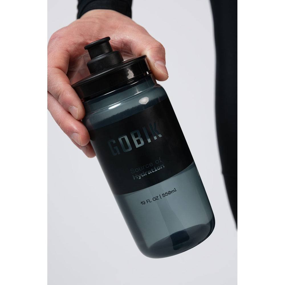 Hand holding GOBIK dark smoked water bottle with push-pull cap against white background