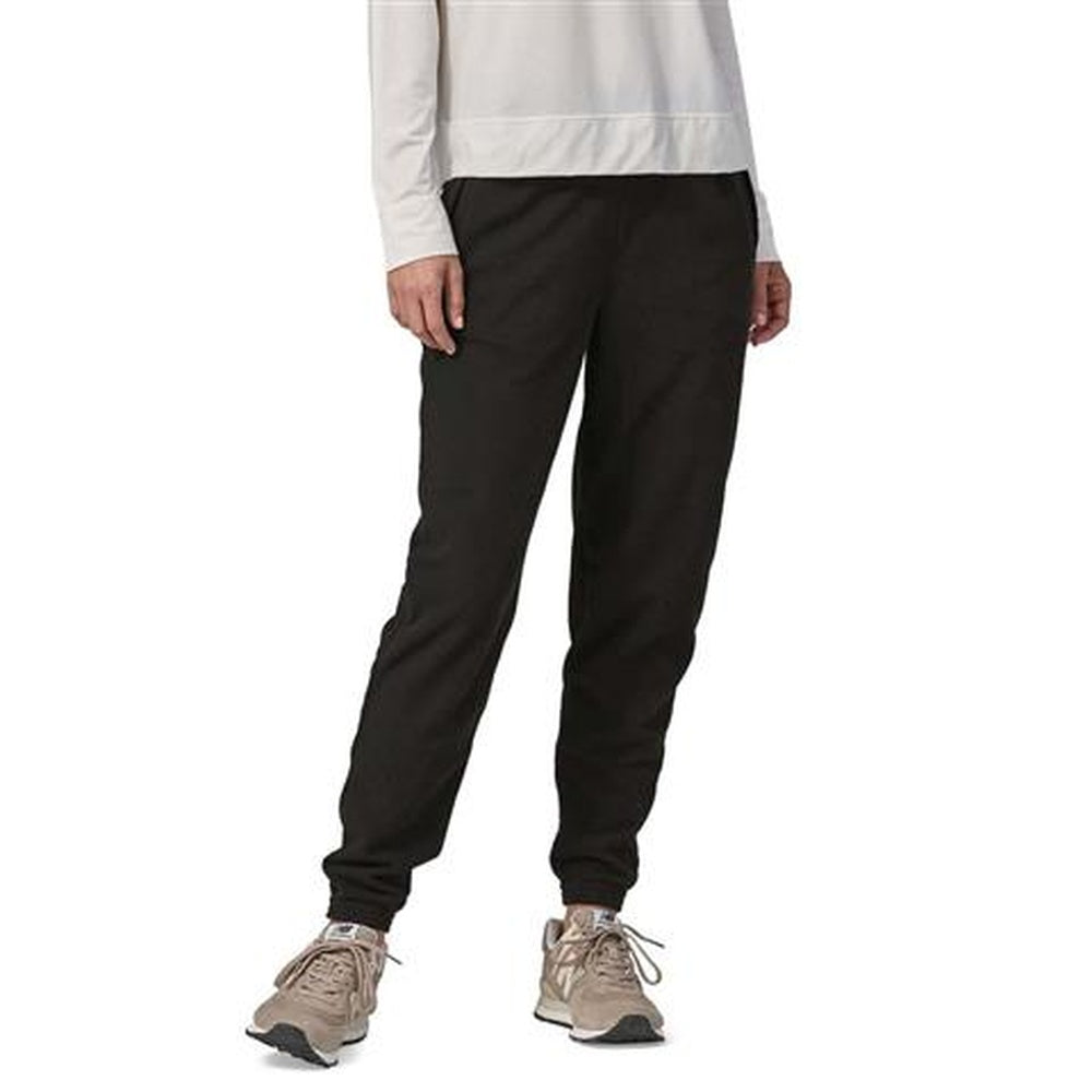 Woman wearing black Patagonia Micro D joggers with beige sneakers on white background